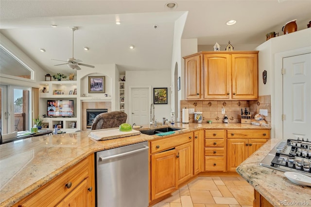 kitchen with sink, ceiling fan, stainless steel appliances, a fireplace, and backsplash