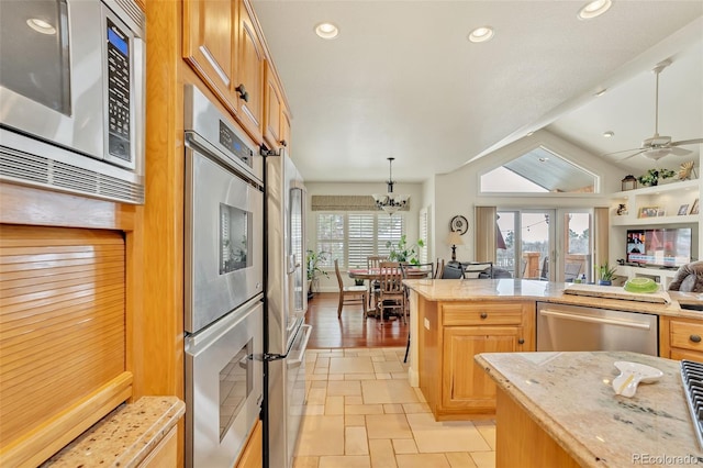 kitchen featuring ceiling fan with notable chandelier, pendant lighting, stainless steel appliances, light stone countertops, and french doors