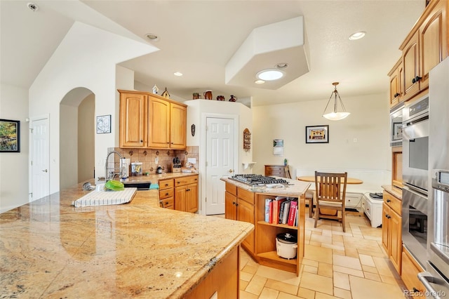 kitchen with sink, light stone counters, decorative backsplash, a kitchen island, and decorative light fixtures