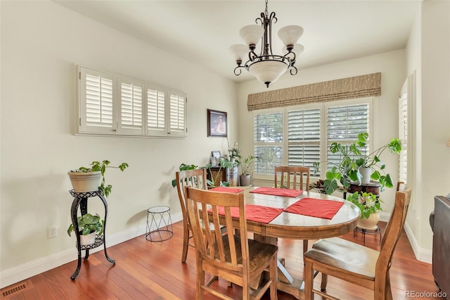 dining space featuring hardwood / wood-style flooring and a chandelier