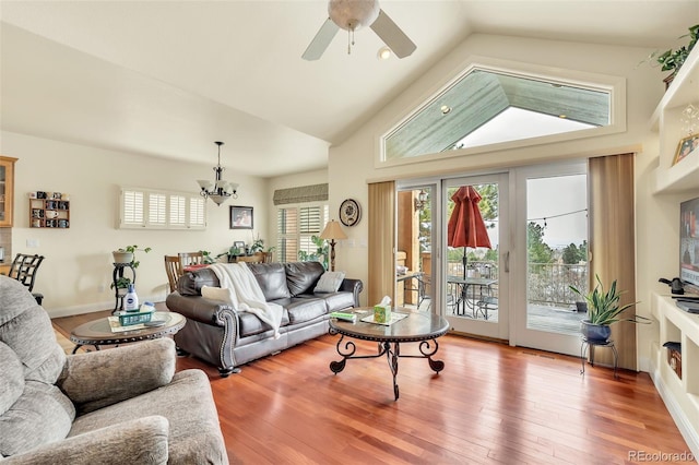 living room featuring lofted ceiling, wood-type flooring, and ceiling fan with notable chandelier