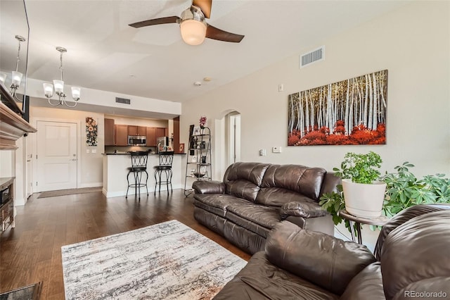 living area featuring arched walkways, ceiling fan with notable chandelier, dark wood-style floors, and visible vents