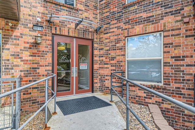 view of exterior entry featuring french doors and brick siding