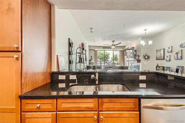 kitchen featuring dark stone countertops, open floor plan, dishwasher, and a sink