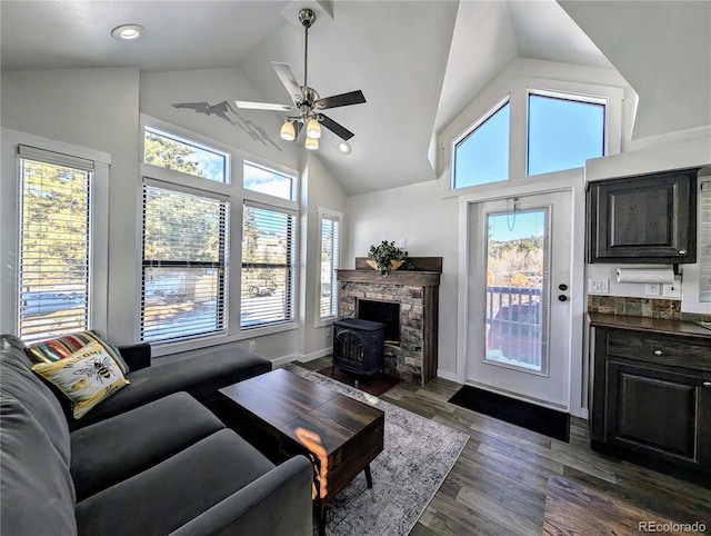 living room featuring high vaulted ceiling, dark hardwood / wood-style floors, a wood stove, and ceiling fan