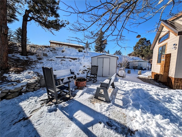 yard covered in snow featuring a fire pit and a storage shed