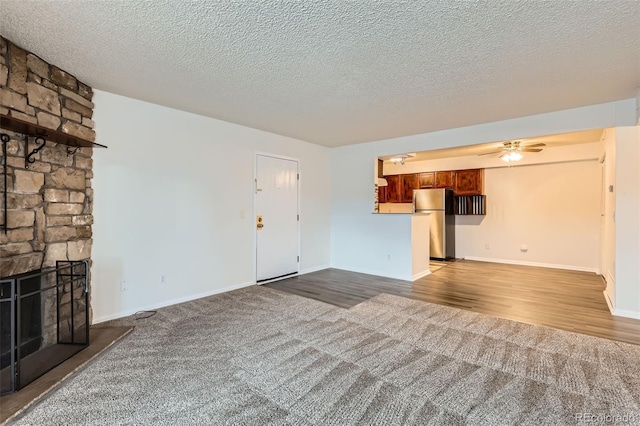 unfurnished living room featuring a fireplace, wood-type flooring, a textured ceiling, and ceiling fan