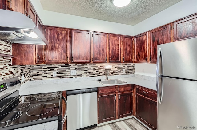 kitchen with sink, stainless steel appliances, tasteful backsplash, light hardwood / wood-style flooring, and a textured ceiling