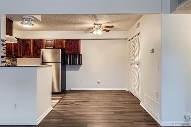 kitchen with a textured ceiling, hardwood / wood-style flooring, stainless steel refrigerator, and ceiling fan