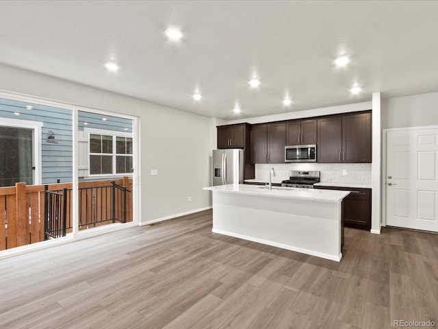 kitchen with wood-type flooring, sink, stainless steel appliances, and an island with sink