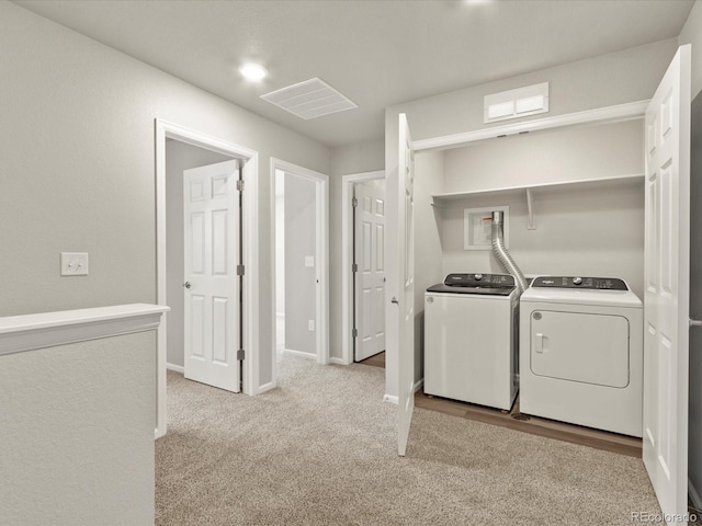 washroom with washing machine and clothes dryer and light carpet