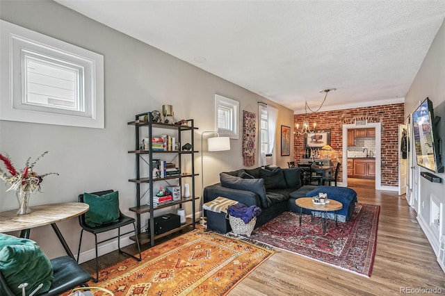 living room with sink, a notable chandelier, brick wall, and hardwood / wood-style floors