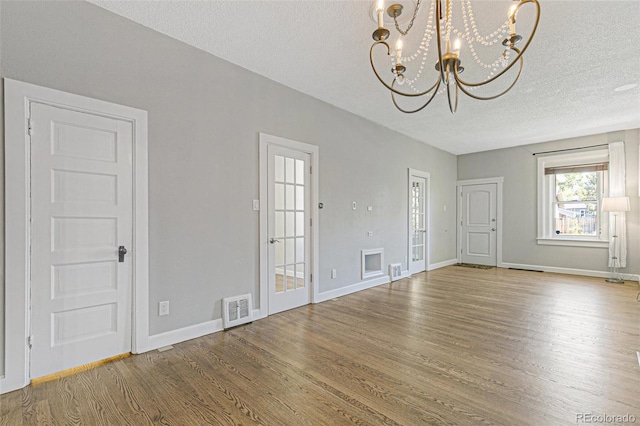 interior space featuring a textured ceiling, a chandelier, and wood-type flooring