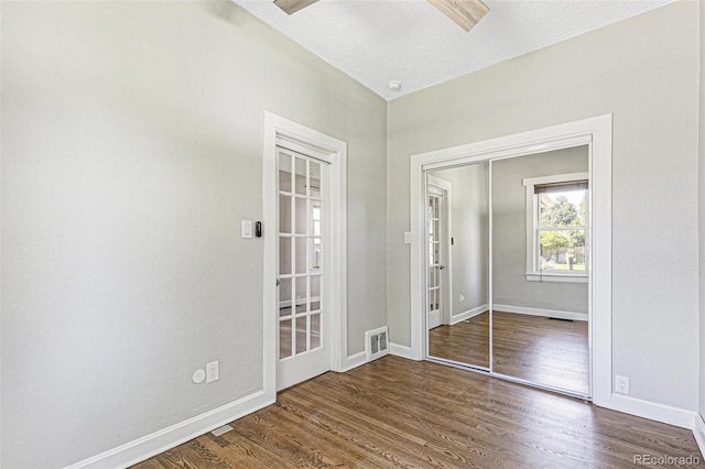 empty room with a textured ceiling and dark hardwood / wood-style floors