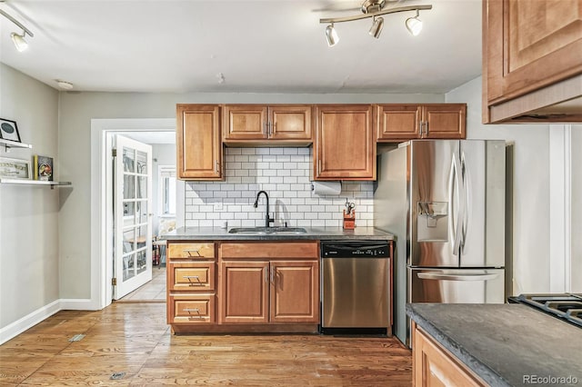 kitchen featuring stainless steel appliances, decorative backsplash, light hardwood / wood-style floors, and sink