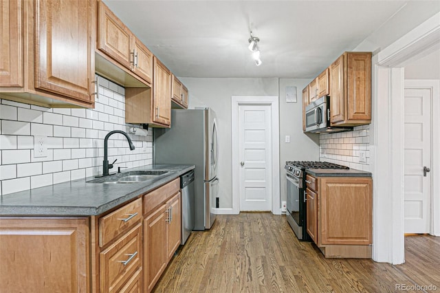 kitchen featuring appliances with stainless steel finishes, backsplash, hardwood / wood-style flooring, and sink