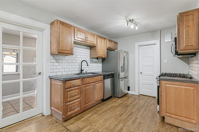 kitchen with sink, appliances with stainless steel finishes, tasteful backsplash, and light wood-type flooring