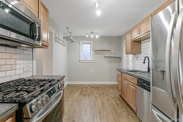 kitchen with tasteful backsplash, sink, stainless steel appliances, and light hardwood / wood-style floors