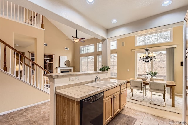 kitchen featuring sink, light tile patterned floors, dishwasher, a high ceiling, and tile counters