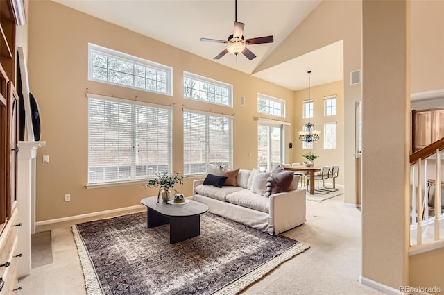 carpeted living room featuring ceiling fan with notable chandelier and high vaulted ceiling