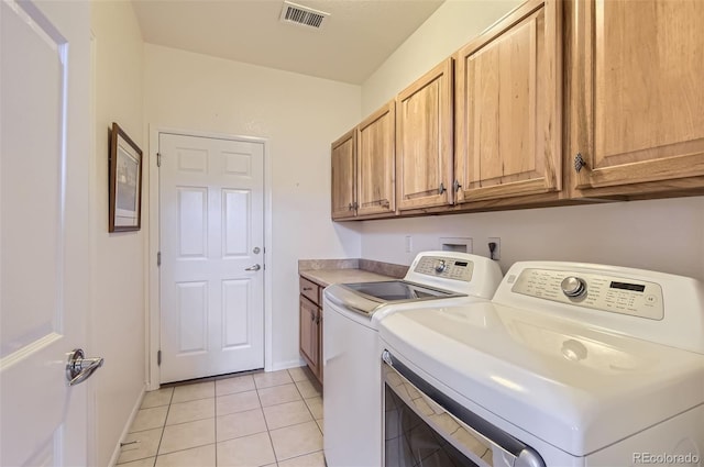 laundry area featuring washer and dryer, light tile patterned flooring, and cabinets