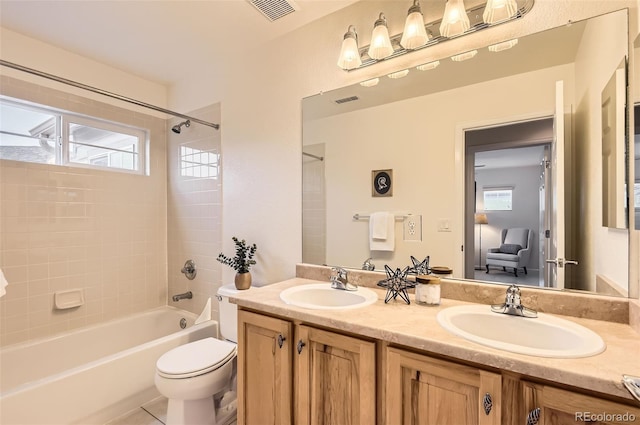 full bathroom with toilet, vanity, and tiled shower / bath combo