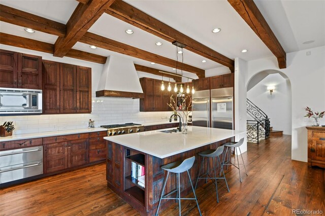 458 Adams St, Denver, CO 80206 - kitchen featuring built in appliances, premium range hood, backsplash, a sink, and beamed ceiling