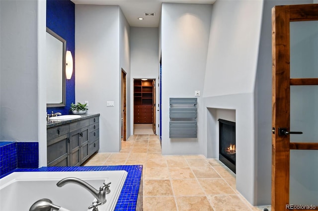 458 Adams St, Denver, CO 80206 - bathroom with vanity, a tub with jets, a lit fireplace, a walk in closet, and a towering ceiling