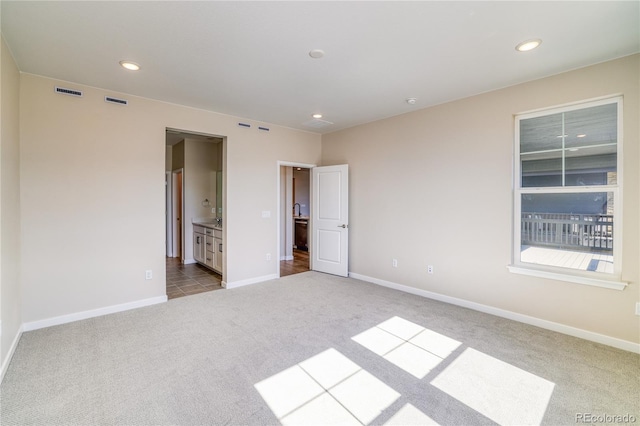 unfurnished bedroom featuring ensuite bath and light carpet