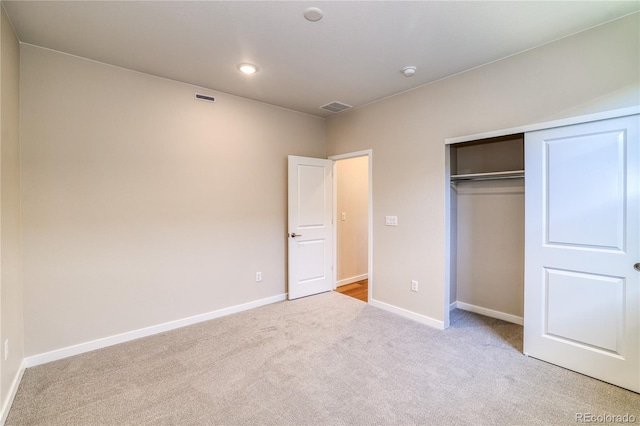 unfurnished bedroom featuring light colored carpet and a closet