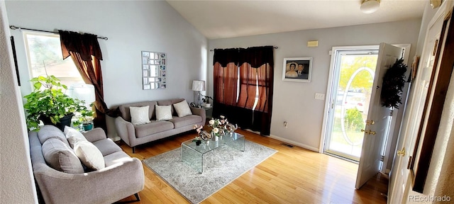 living room with lofted ceiling, a wealth of natural light, and hardwood / wood-style floors