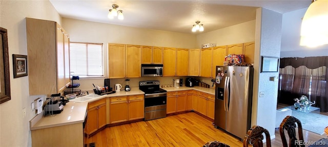 kitchen with sink, stainless steel appliances, and light hardwood / wood-style floors