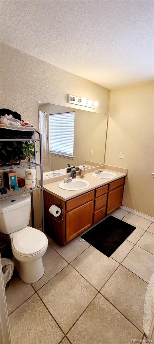 bathroom featuring vanity, toilet, tile patterned floors, and a textured ceiling