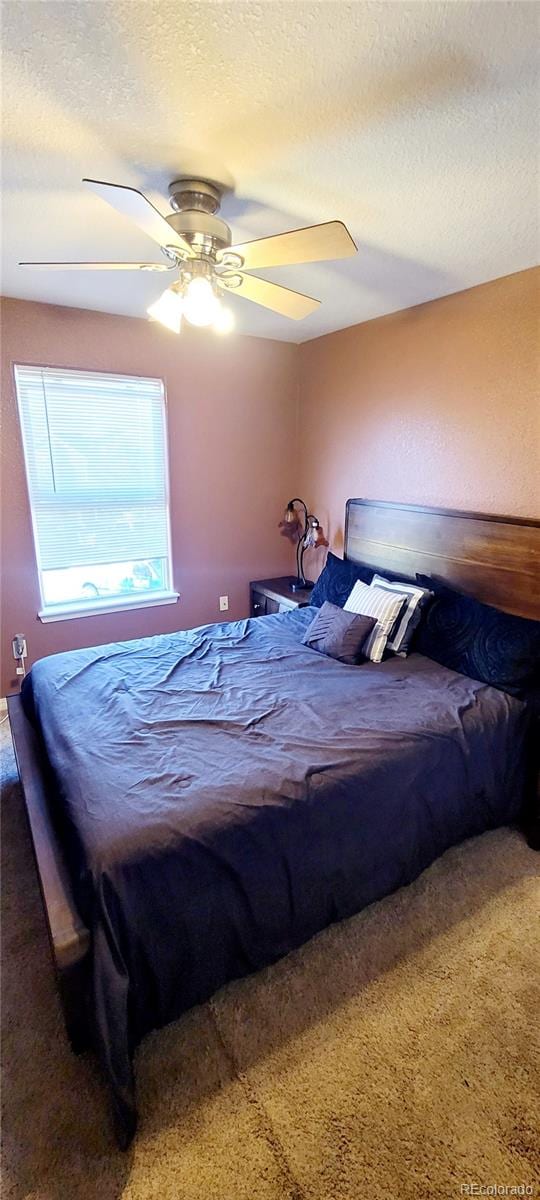 bedroom with a textured ceiling, carpet floors, and ceiling fan