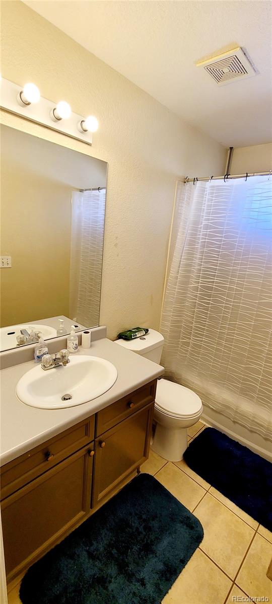 bathroom with toilet, curtained shower, vanity, and tile patterned flooring