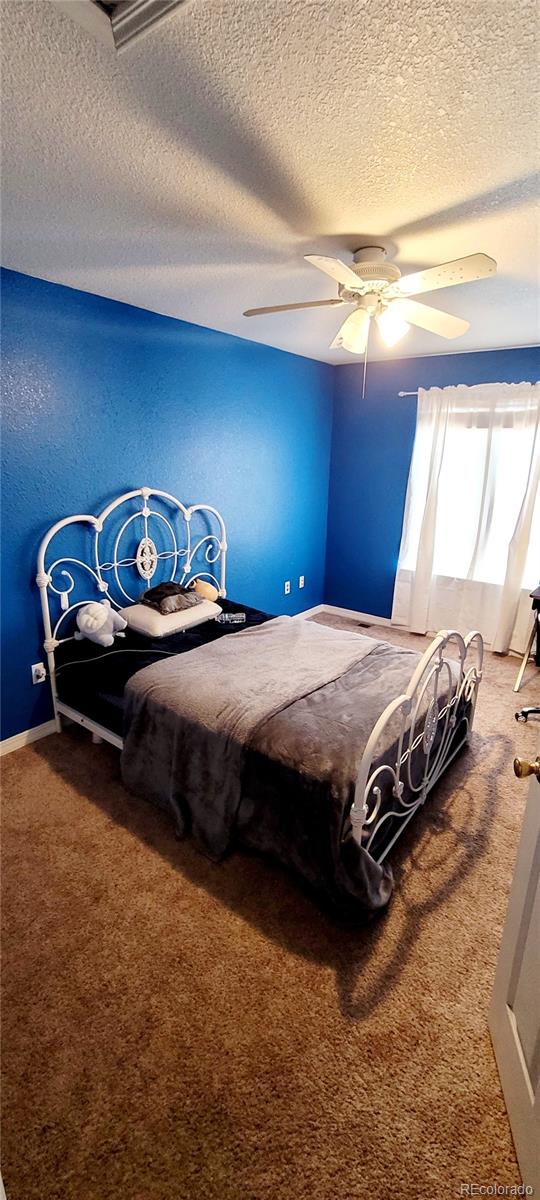 bedroom with a textured ceiling, carpet floors, and ceiling fan