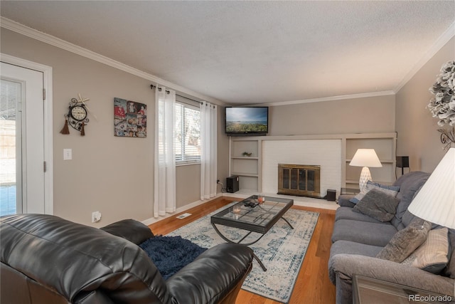 living room with crown molding, a fireplace, a textured ceiling, and light hardwood / wood-style flooring