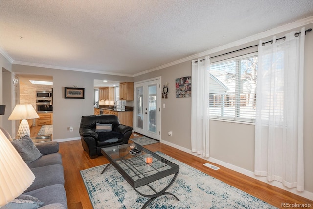 living room featuring hardwood / wood-style flooring, ornamental molding, and a textured ceiling