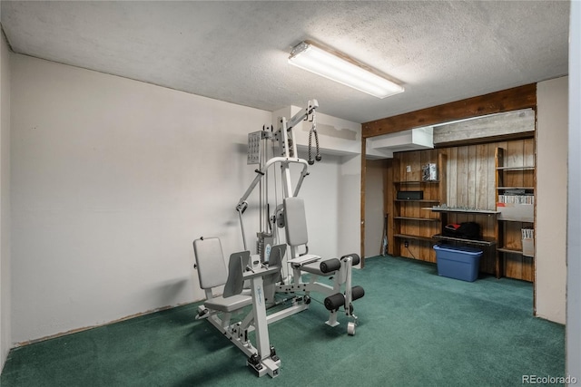 exercise area featuring dark carpet and a textured ceiling