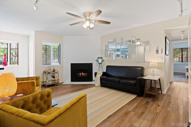534 E 7th Ave Unit 101, Denver, CO 80203 - living room featuring rail lighting, wood-type flooring, ceiling fan, and a large fireplace