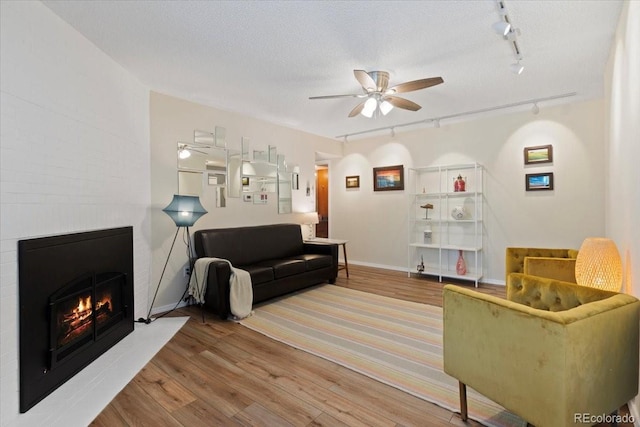 534 E 7th Ave Unit 101, Denver, CO 80203 - living area featuring track lighting, ceiling fan, wood finished floors, a large fireplace, and baseboards