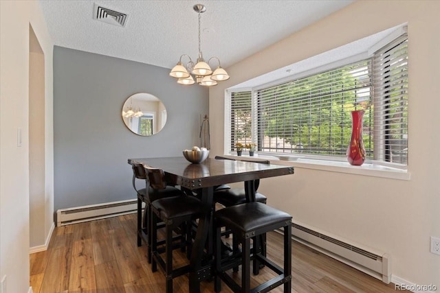 534 E 7th Ave Unit 101, Denver, CO 80203 - dining area with baseboard heating, a baseboard radiator, a chandelier, a textured ceiling, and wood finished floors