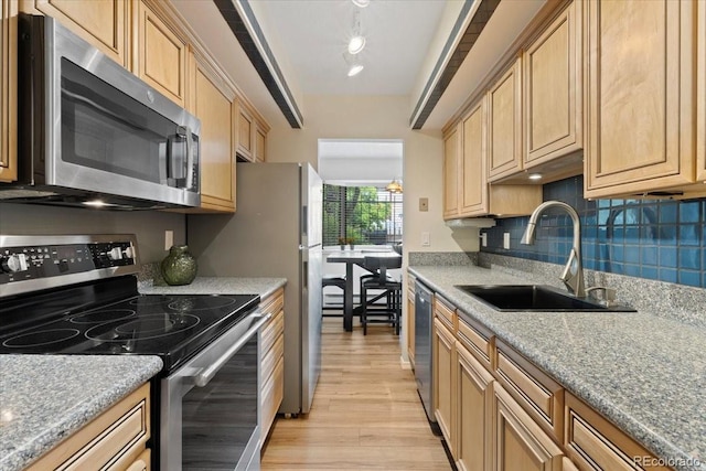 534 E 7th Ave Unit 101, Denver, CO 80203 - kitchen featuring stainless steel appliances, a sink, light wood-type flooring, tasteful backsplash, and light brown cabinetry
