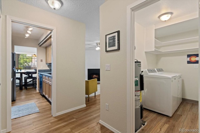 534 E 7th Ave Unit 101, Denver, CO 80203 - laundry room with washing machine and dryer, a ceiling fan, light wood-type flooring, a large fireplace, and baseboards