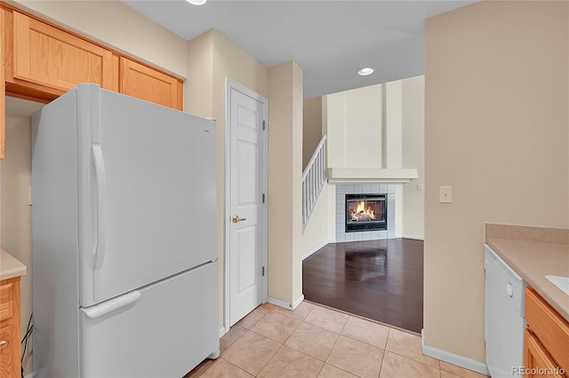 4006 E Geddes Cir, Centennial, CO 80122 - kitchen with white appliances, light tile patterned flooring, light brown cabinetry, a tiled fireplace, and light countertops