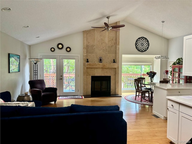 5479 E Weaver Ave, Centennial, CO 80121 - living room featuring light wood-style flooring, a ceiling fan, a textured ceiling, a tile fireplace, and high vaulted ceiling