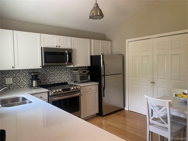 5479 E Weaver Ave, Centennial, CO 80121 - kitchen with stainless steel appliances, vaulted ceiling, backsplash, light countertops, and light wood-type flooring