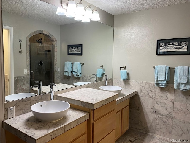 5479 E Weaver Ave, Centennial, CO 80121 - full bathroom featuring a textured ceiling, a stall shower, vanity, tile walls, and a wainscoted wall