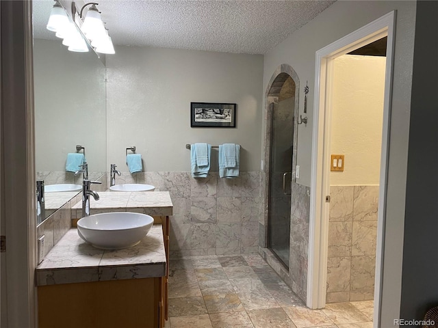 5479 E Weaver Ave, Centennial, CO 80121 - full bathroom featuring tile walls, a textured ceiling, double vanity, a stall shower, and a wainscoted wall