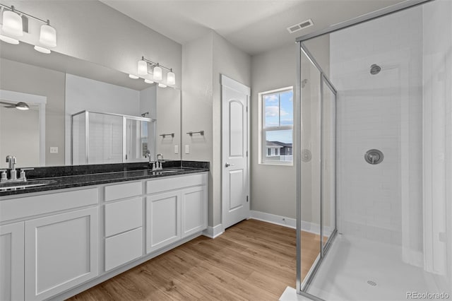 21034 E 63rd Dr, Aurora, CO 80019 - bathroom featuring a shower stall, double vanity, and wood finished floors